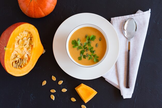 Soupe de citrouille traditionnelle de saison avec des graines dans un bol sur fond noir. vue de dessus.