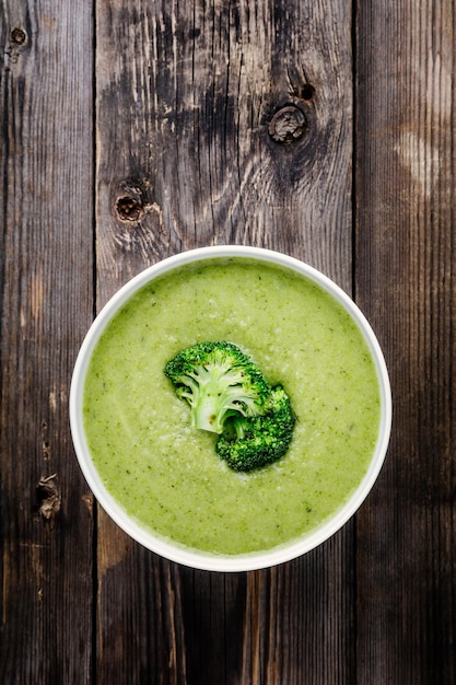 Soupe à la crème de brocoli maison dans un bol blanc avec des toasts sur fond rustique en bois