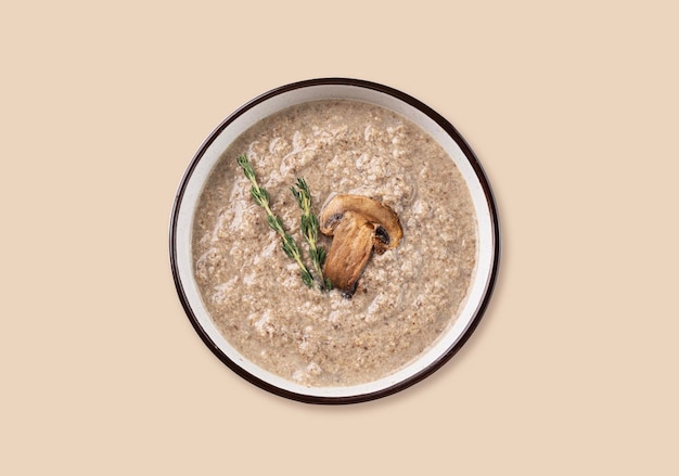 Soupe crème de champignons au thym dans un bol en céramique sur un fond beige isolé Le concept de nourriture végétarienne et diététique