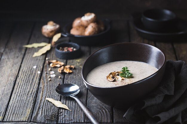 Soupe à la crème de champignons dans un bol sur une surface en bois sombre