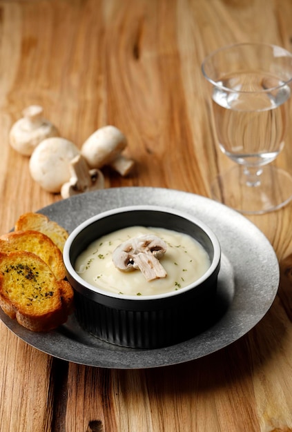 Soupe à la crème de champignons avec du pain à l'ail croustillant sur table en bois