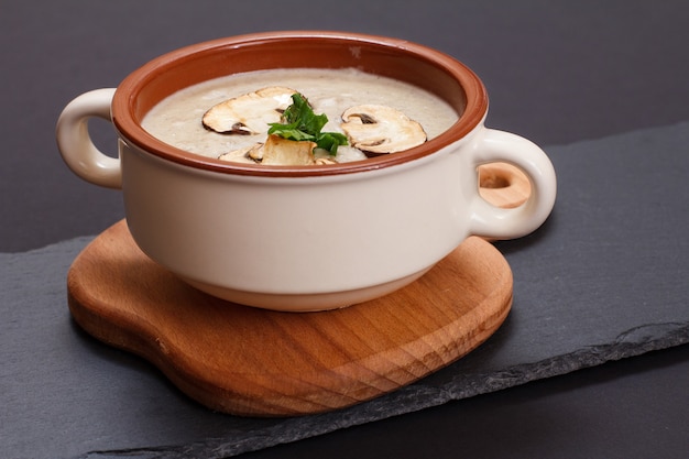 Soupe à la crème de champignons maison dans un bol en porcelaine avec des champignons tranchés. Vue de dessus.
