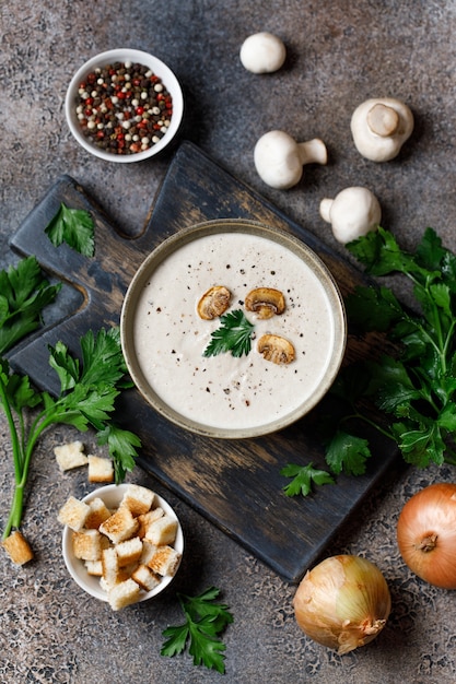 Soupe à la crème de champignons sur une planche à découper avec des ingrédients