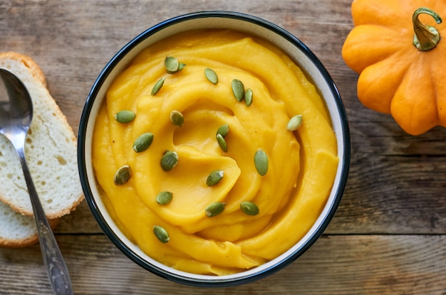 Soupe à la crème de citrouille épaisse avec des graines sur un fond en bois