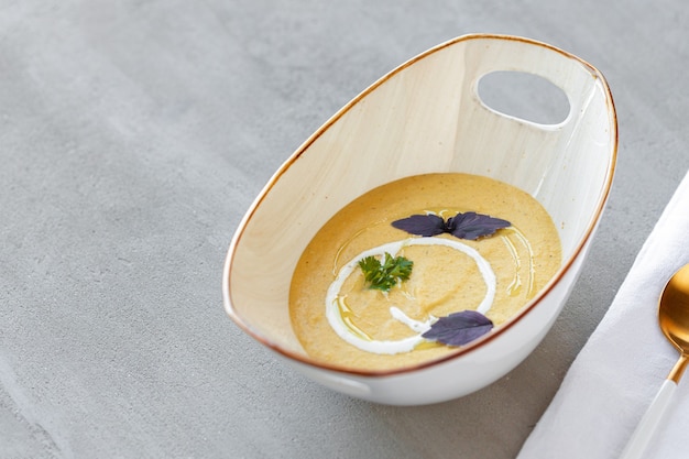 Soupe à la crème de légumes dans un bol sur une table grise