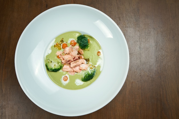 Soupe à la crème de pois verts appétissante et saine avec du brocoli et du saumon cuit dans un fumoir sur une table en bois. Vue de dessus