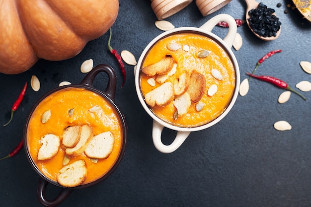 Soupe à la crème de potiron avec croûtons sur une table noire avec des épices. Photo de haute qualité