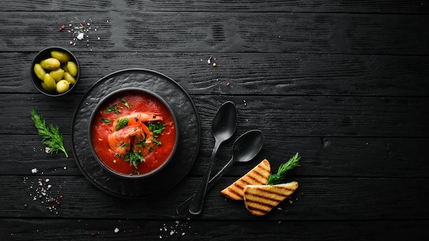 Soupe à la crème de tomates aux crevettes dans un bol noir Menu de fruits de mer Vue de dessus Style rustique