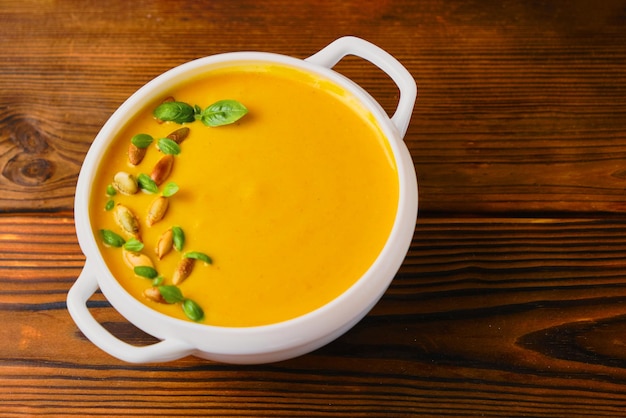 Soupe crémeuse à la citrouille dans un bol avec graines et basilic