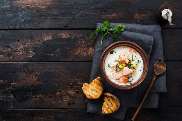 Soupe crémeuse finlandaise tiède au saumon et légumes dans un vieux bol en céramique