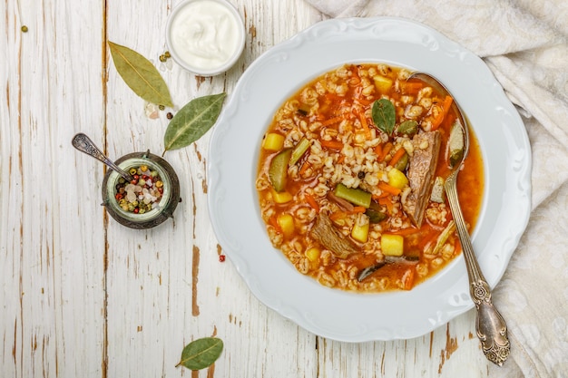 Soupe épaisse et consistante avec du bœuf, des légumes (cornichons, carottes, oignons, pommes de terre, tomates) et de l'orge perlé