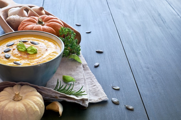 Soupe épicée à la crème de citrouille au gingembre, oignon et ail sur bois bleu