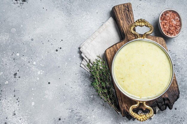 Photo soupe française traditionnelle vichyssoise à base de pomme de terre poireau et d'oignon dans une casserole fond gris vue de dessus espace de copie