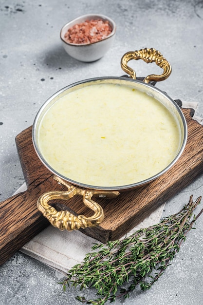 Photo soupe française traditionnelle vichyssoise à base de pommes de terre poireaux et oignons dans une casserole fond gris vue de dessus