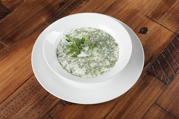 Soupe froide traditionnelle russe et ukrainienne okroshka dans une assiette blanche. Fond en bois