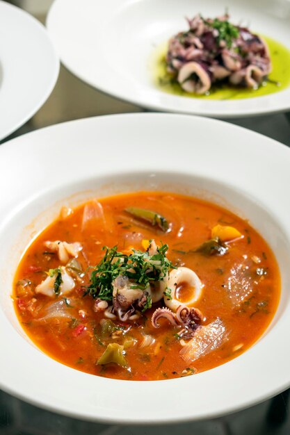 Photo soupe de fruits de mer à la calmar bouillie dans une sauce épicée de tomates et de légumes