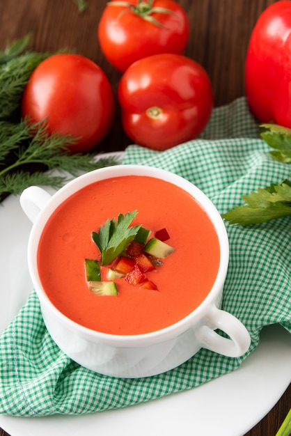 Photo soupe de gaspacho espagnol sur fond de bois avec des tomates et des herbes.