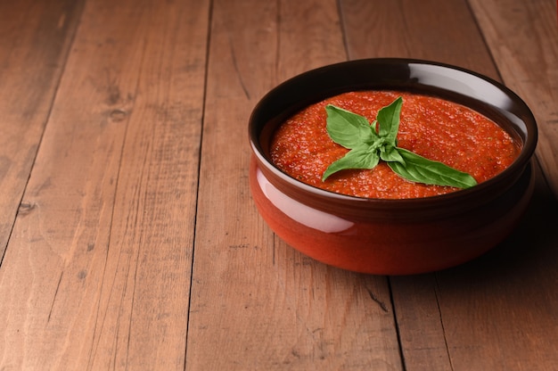 Soupe de gaspacho froide à la tomate espagnole dans un bol avec du basilic. Gaspacho fait maison préparé par des tomates rouges.