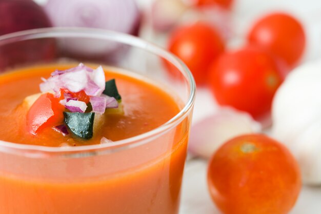 Photo soupe de gaspacho en verre sur une table en bois blanc se bouchent