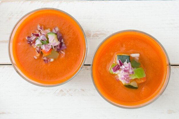 Soupe de gaspacho en verre sur une table en bois blanc