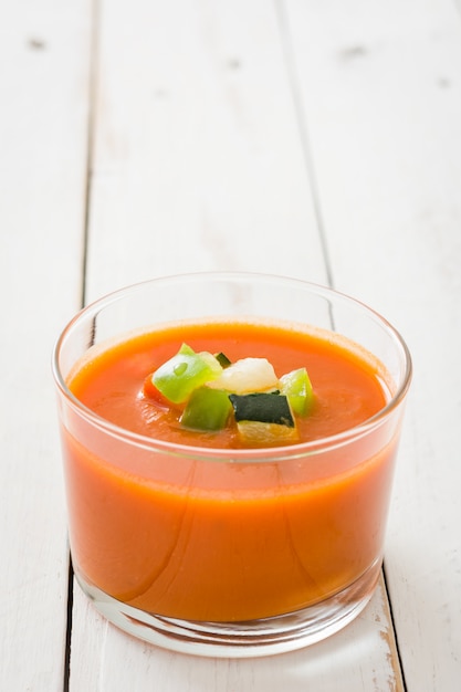 Soupe de gaspacho en verre sur une table en bois blanc