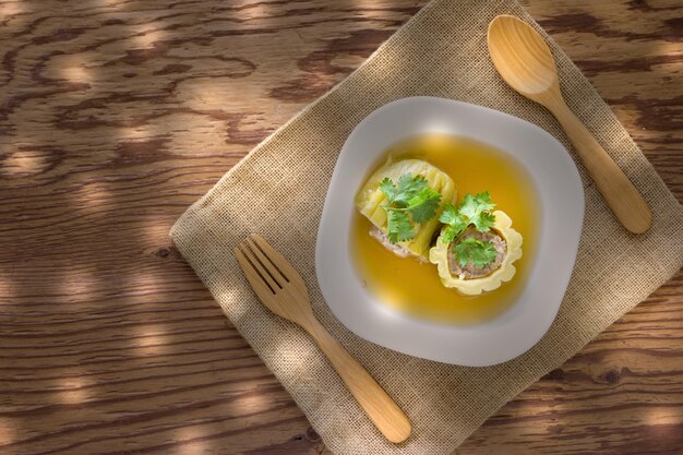 Soupe de gourd amère farcie avec du porc haché assaisonné sur fond de bois