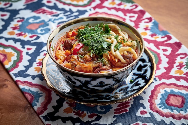 Soupe Laghman avec viande, légumes et nouilles effilochées servie en assiette.