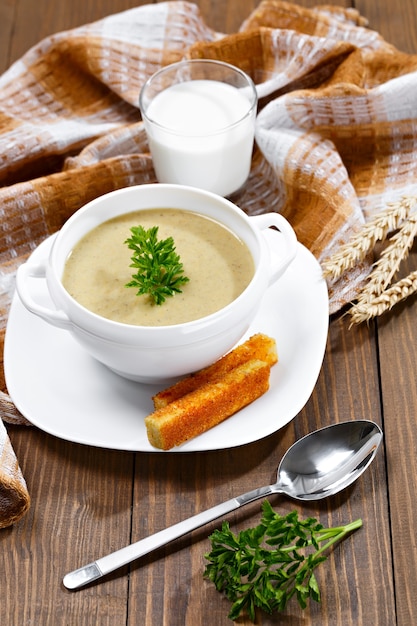 Soupe de légumes au persil et pain frit sur une table en bois.