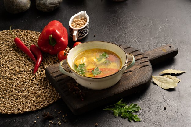 Soupe de légumes au saumon, pommes de terre et poivrons garnie de feuilles de laurier persil et de tomates cerises.