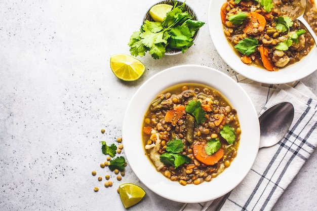 Soupe de lentilles aux légumes dans une assiette blanche, fond blanc. Aliments à base de plantes, alimentation propre.