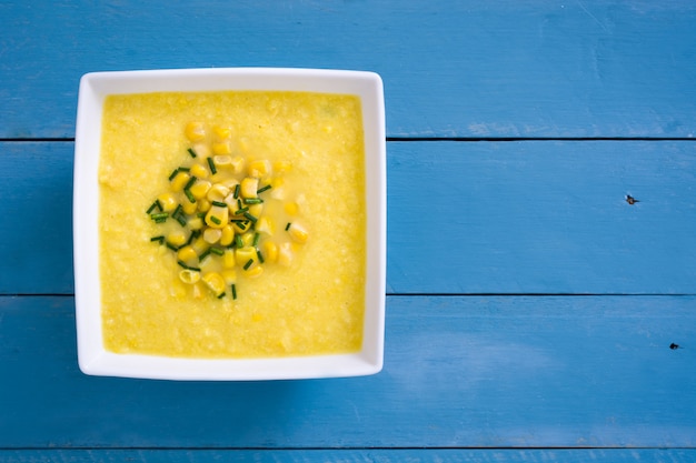 Soupe de maïs dans un bol sur une surface en bois bleue