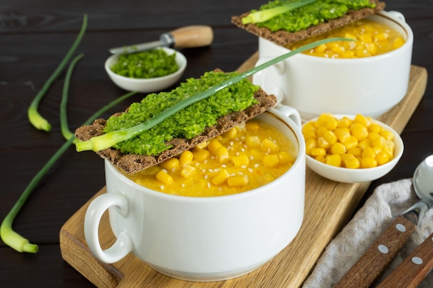 Photo soupe de maïs avec pate d'ail frais dans un bol blanc. nourriture saine sur fond en bois. cuisine végétalienne