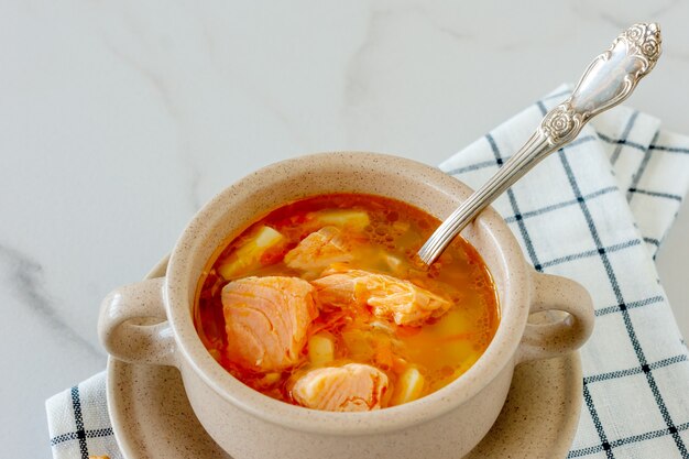 Soupe maison au saumon avec des bâtonnets de pain sur marbre