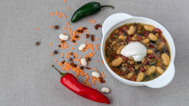 Soupe mexicaine de sept sortes de haricots à la crème sure en gros plan sur un fond de lin gris entouré