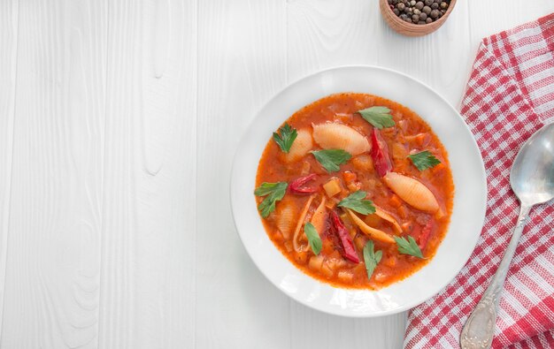 Soupe minestrone aux pâtes et aux herbes. Cuisine italienne. Plat végétarien. Table à dinner. Fond en bois blanc. Copiez l'espace.