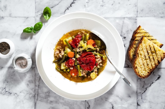 Soupe minestrone italienne d'été avec tomates et pain fait maison sur une table en marbre