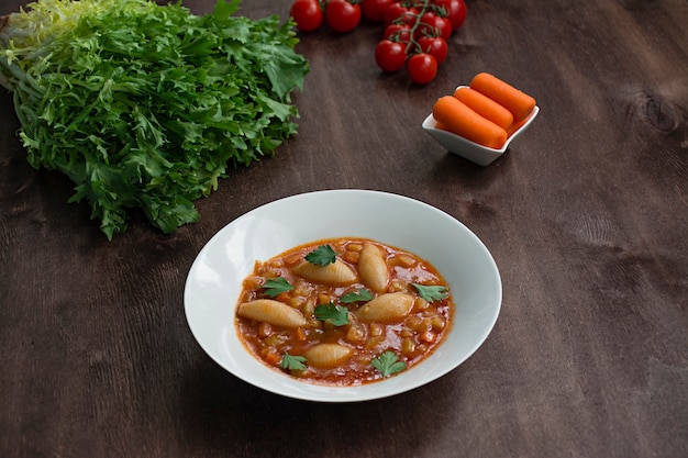 Soupe Minestrone avec des pâtes et des herbes. Cuisine italienne. Fond en bois foncé