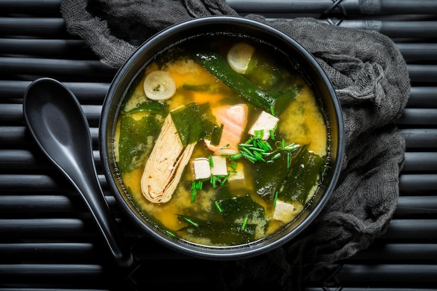 Soupe miso au saumon dans un bol noir sur tableau noir