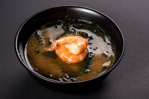 Soupe miso chaude aux crevettes dans un bol sur fond noir Cuisine japonaise