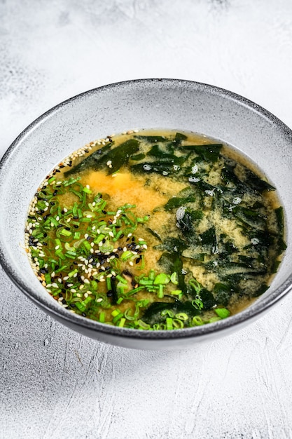 Soupe miso japonaise dans un bol blanc. Fond blanc. Vue de dessus