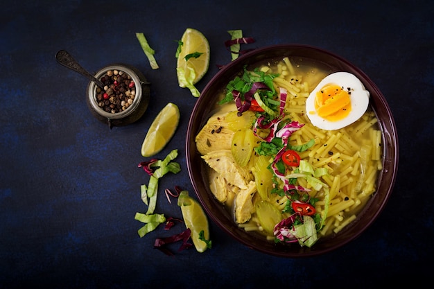 Soupe de nouilles au poulet, céleri et oeuf dans un bol sur un fond en bois ancien.