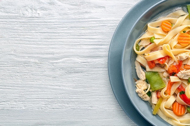 Soupe de nouilles au poulet dans une assiette sur fond de bois