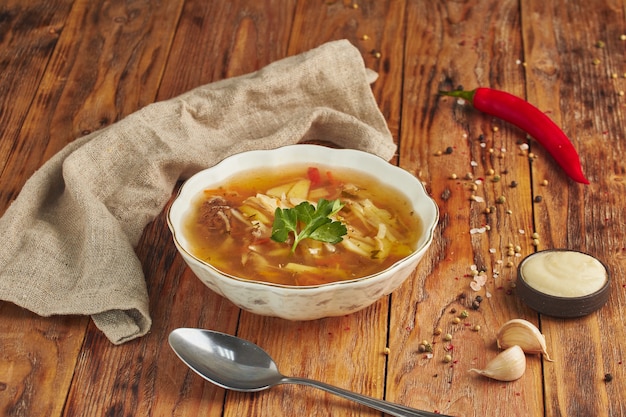 Soupe de nouilles dans un bol, cuillère sur table en bois