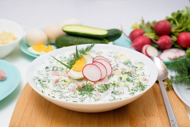 Soupe Okroshka froide nationale russe dans une assiette blanche sur fond clair.