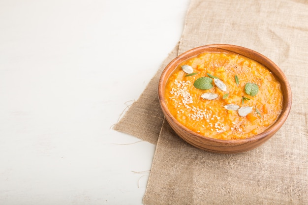 Soupe de patate douce ou batata aux graines de sésame dans un bol en bois sur un fond en bois blanc. vue latérale, espace copie.