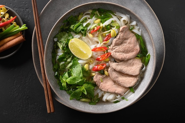 Soupe pho bo au boeuf dans un bol sur fond noir cuisine vietnamienne