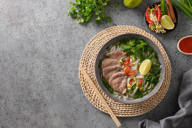 Soupe Pho bo au boeuf dans un bol gris sur fond gris cuisine vietnamienne