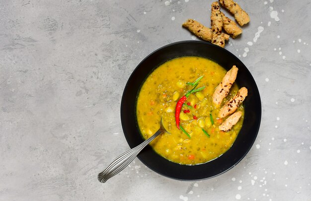 Soupe de pois cassés au poulet et haricots verts avec des bâtons de pain avec des piments rouges et des oignons verts, recette de la cuisine asiatique