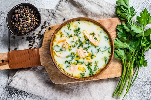 Soupe de poisson crémeuse au saumon, truite, pommes de terre et persil. Fond gris, vue de dessus.