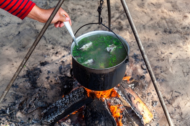 Soupe de poisson cuisinant dans une casserole sur un feu dans la forêt au bord de la mer